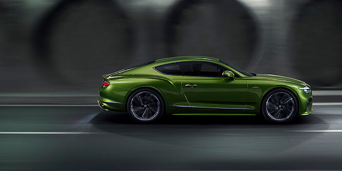  Bentley Leicester Bentley Continental GT coupe in Tourmaline Green paint driving in profile on a dark road