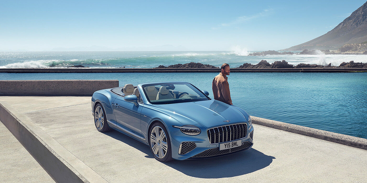 Bentley Leicester New Bentley Continental GTC Azure convertible front view in Light Windsor blue paint with 22 inch ten spoke wheels parked by the sea in the sunshine