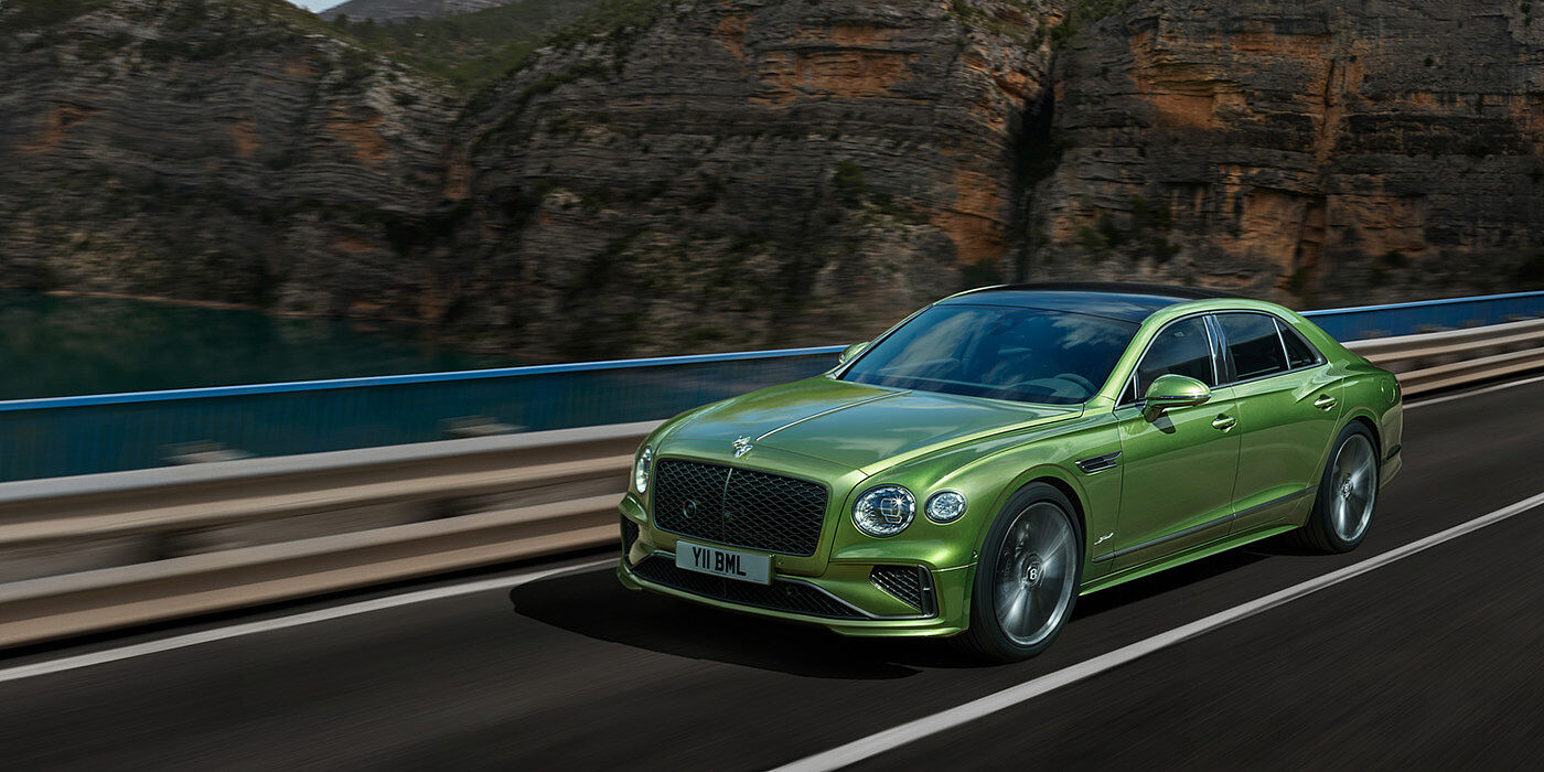 Bentley Leicester Bentley New Flying Spur Speed v8 hybrid sedan driving dynamically on a mountain road in Tourmaline Green paint