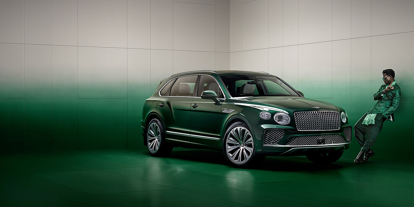 Bentley Leicester Wisdom K leans against wall next to Bentley Bentayga Extended Wheelbase Atelier Edition SUV in Light Emerald green paint