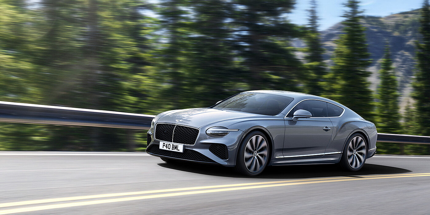 Bentley Leicester New Bentley Continental GT coupe in Silverlake paint and 22 inch ten-spoke wheels, driving dynamically on a tree-lined road in the sunshine