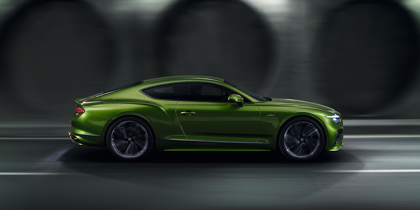 Bentley Leicester Bentley Continental GT coupe in Tourmaline Green paint driving in profile on a dark road