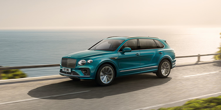 Bentley Leicester Bentley Bentayga Extended Wheelbase Azure SUV in Topaz blue paint driving dynamically by the ocean