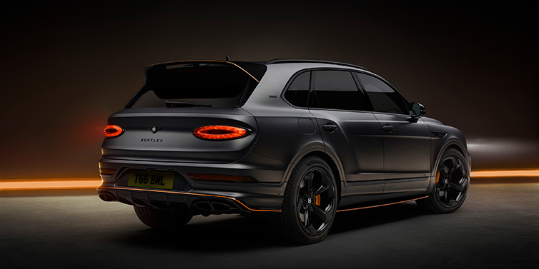 Bentley Leicester Bentley Bentayga S Black Edition SUV rear three quarter in Anthracite Satin paint against a dark red and yellow background